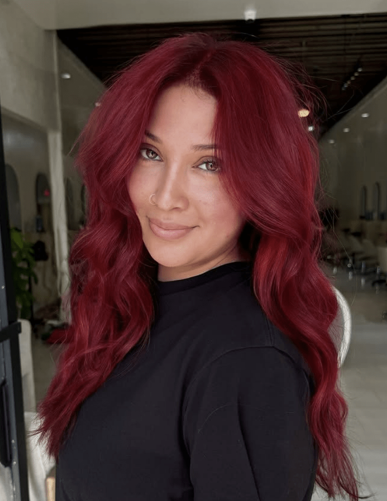 Chica con pelo largo ondulado en un tono rojo.