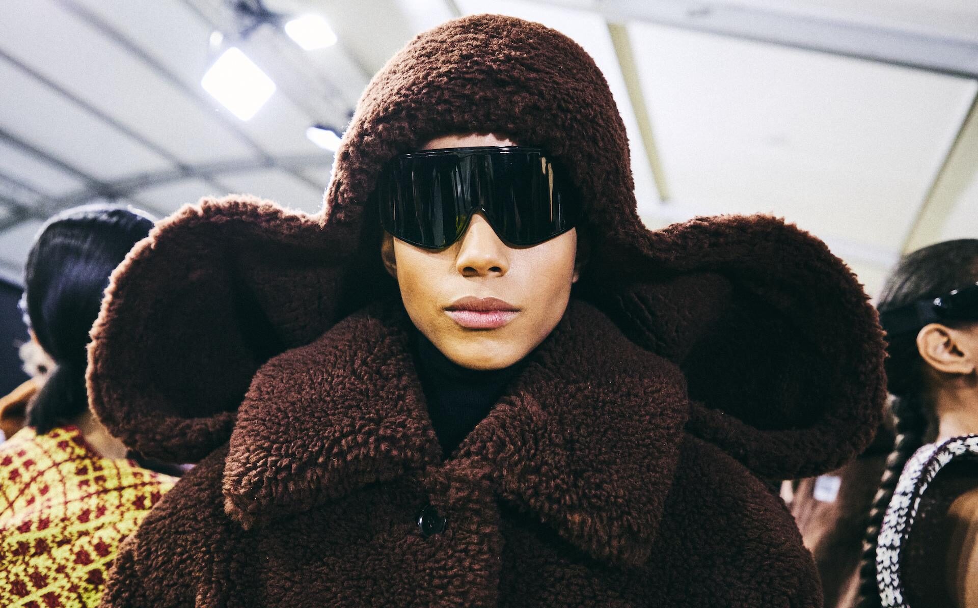 Look del desfile Loewe otoño-invierno 2026 con abrigo de borrego oversize, capucha escultórica y gafas futuristas, reflejando la nueva era creativa de Lazaro Hernández y Jack McCollough. Imagen: ©Molly SJ Lowe