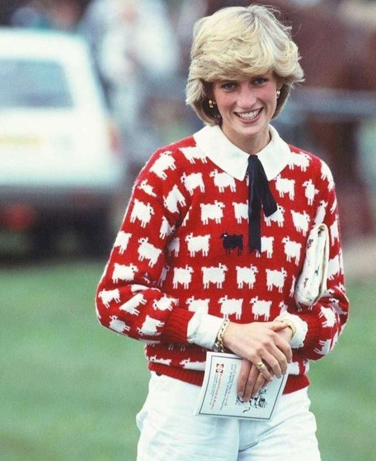 Diana de Gales con jersey rojo de ovejas blancas y una oveja negra durante un partido de polo 