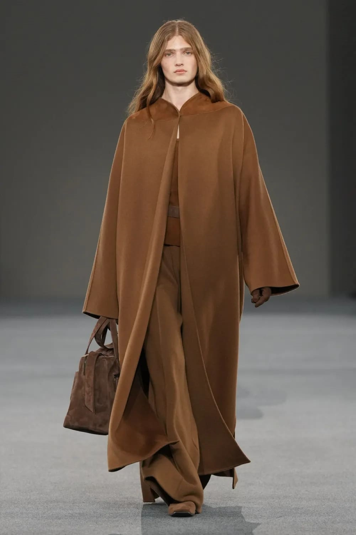 La capa-abrigo marrón del look 6 de Max Mara FW 2026/2027 envuelve la silueta con un volumen fluido y mangas amplias, en un estilismo monocolor de inspiración sofisticada