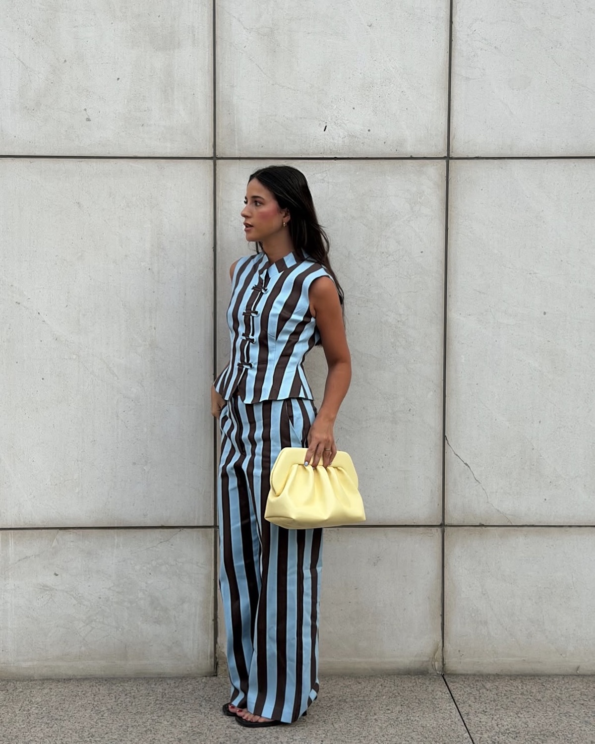 Look de conjunto de rayas y bolso amarillo en forma de contraste