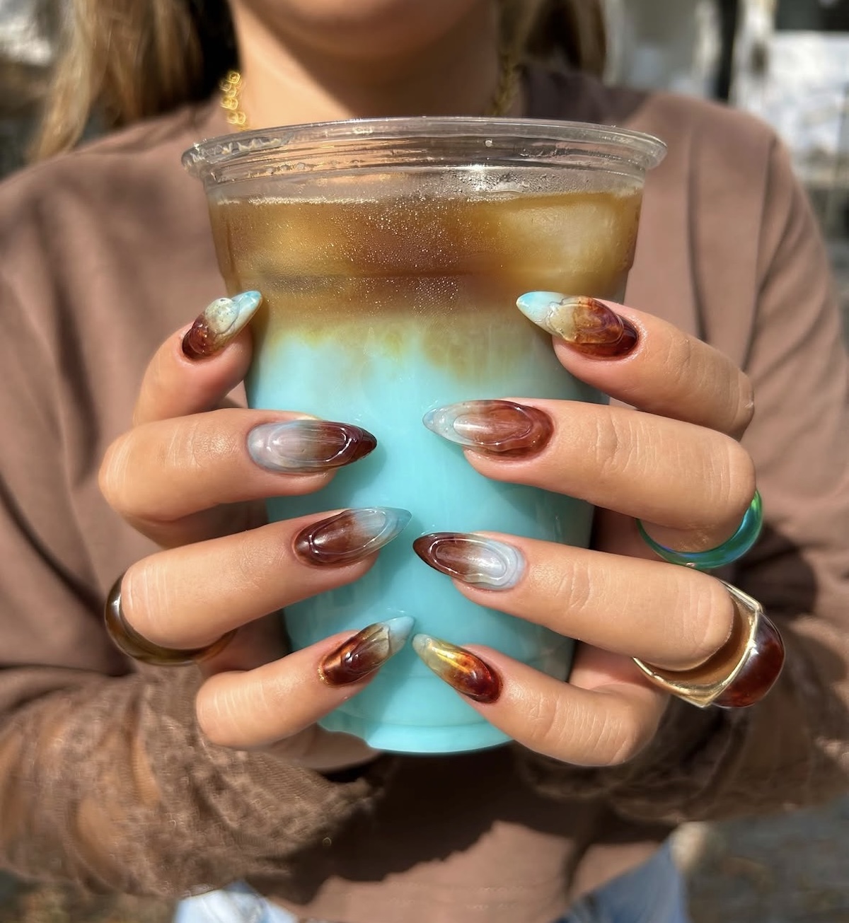 Manicura marrón y turquesa, una de las mejores formas de llevar las «cappuccino nails». Imagen: @encantadakarolacevedo