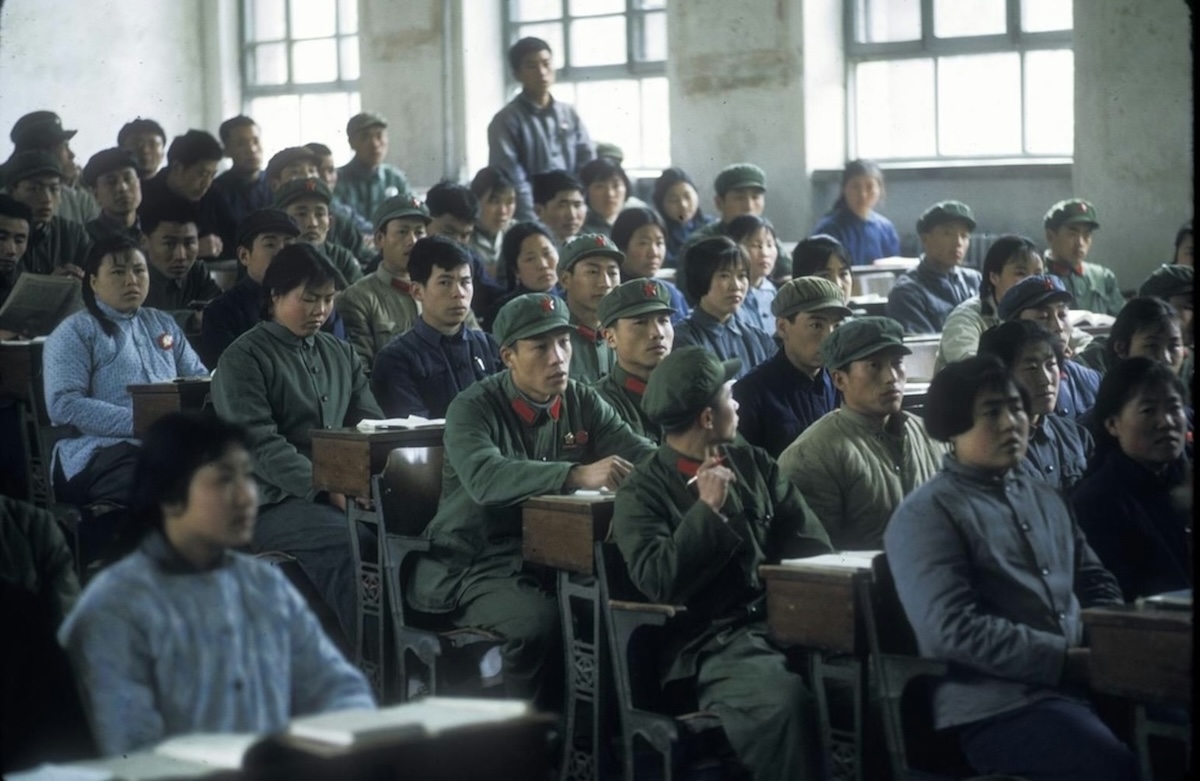 La imagen muestra a un grupo de estudiantes obreros, campesinos y soldados en una clase universitaria de China a principios de la década de 1970, durante la Revolución Cultural, con el uniforme Mao