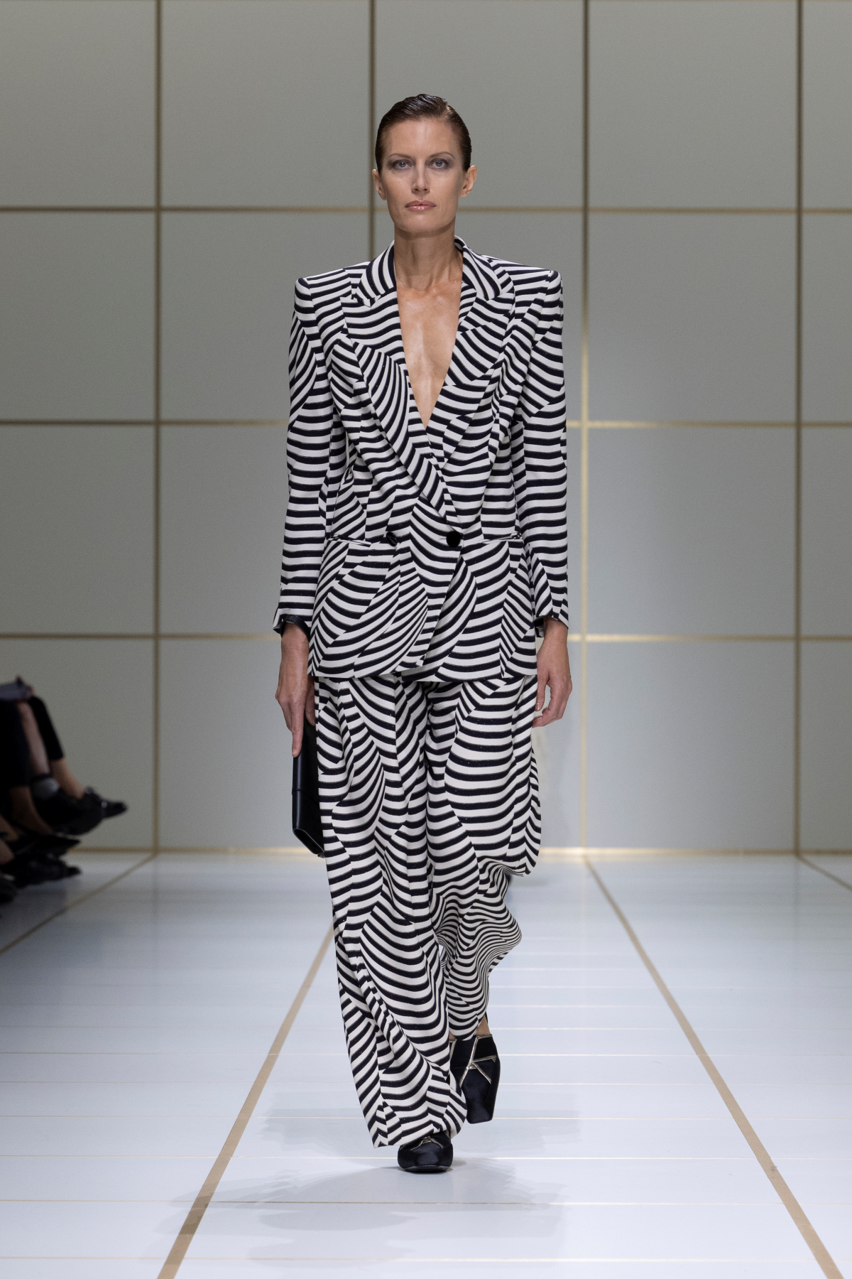 Look 9 de Giorgio Armani Primavera-Verano 2027, con americana de rayas blancas y negras, escote en V profundo, pantalón a juego y bolso de mano negro