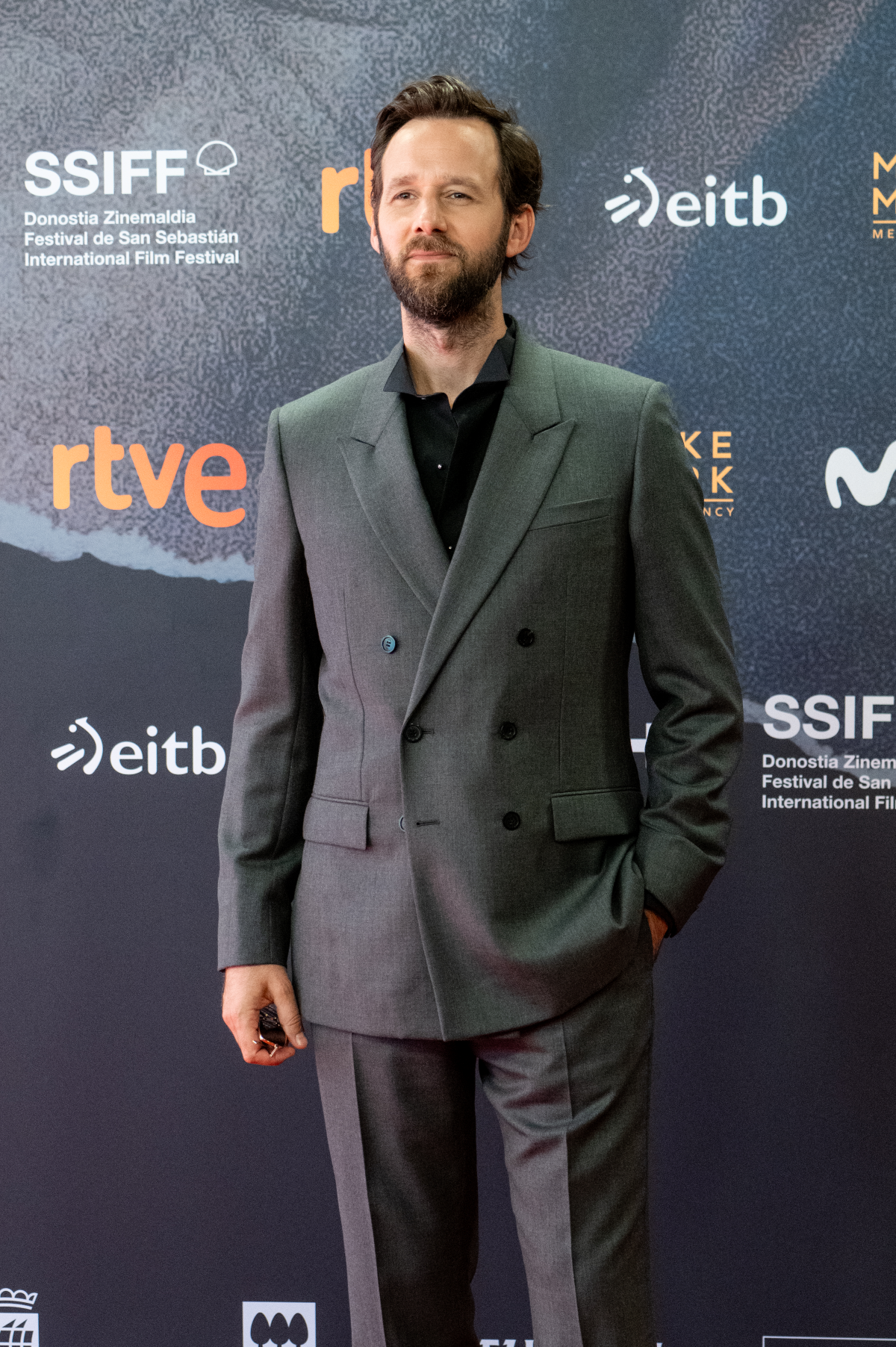 Benjamin Lavernhe posa con un traje gris de lana de Dior de doble botonadura y solapas en pico, combinado con una camisa negra de algodón con cuello de alas