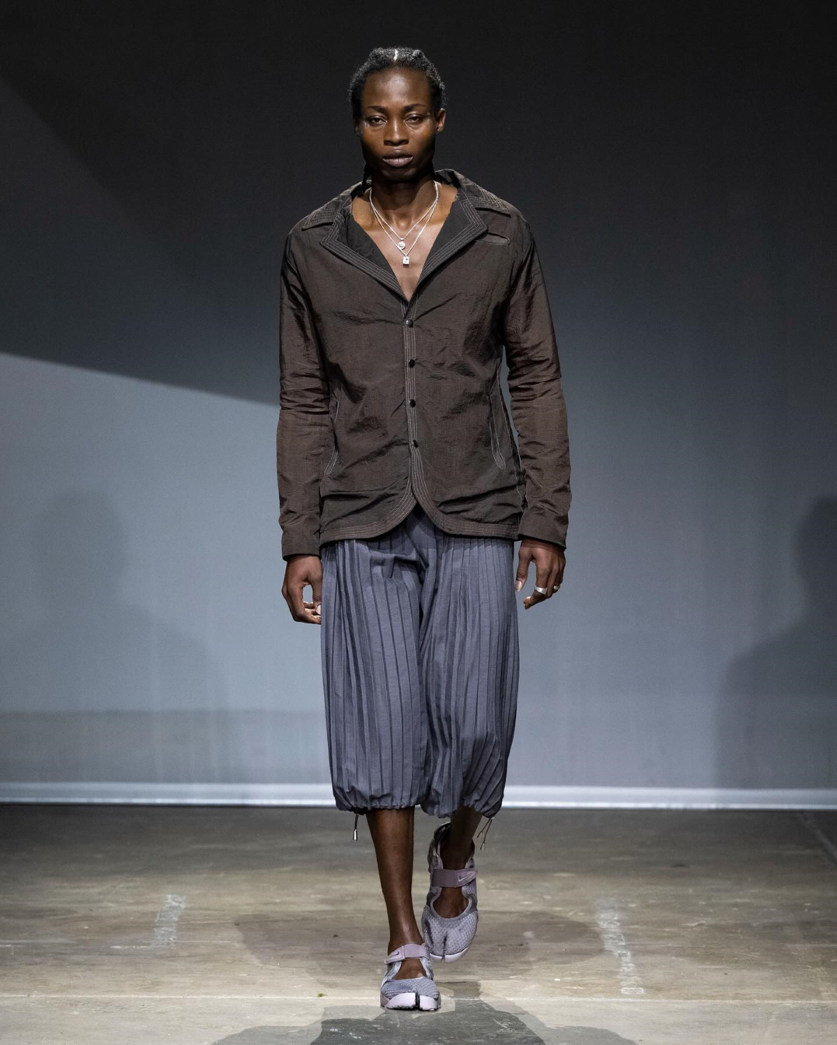 Modelo Teddy luce el look 1 de la Season 7 de Charlie Constantinou, compuesto por una americana de ripstop teñida, shorts de lino plisados y unas Nike Air Rift teñidas