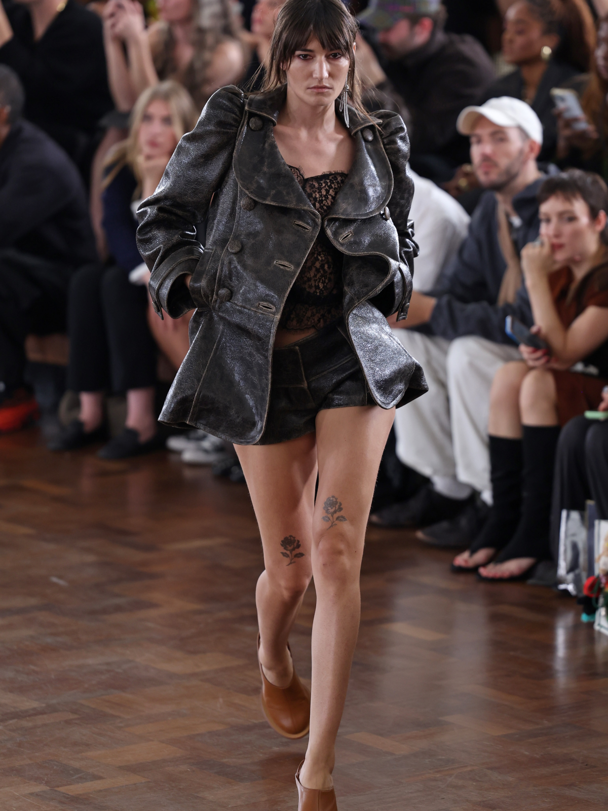 Modelo luce el look 23 de KNWLS para Primavera-Verano 2027, formado por un estilismo negro con rosas negras pintadas sobre las rodillas