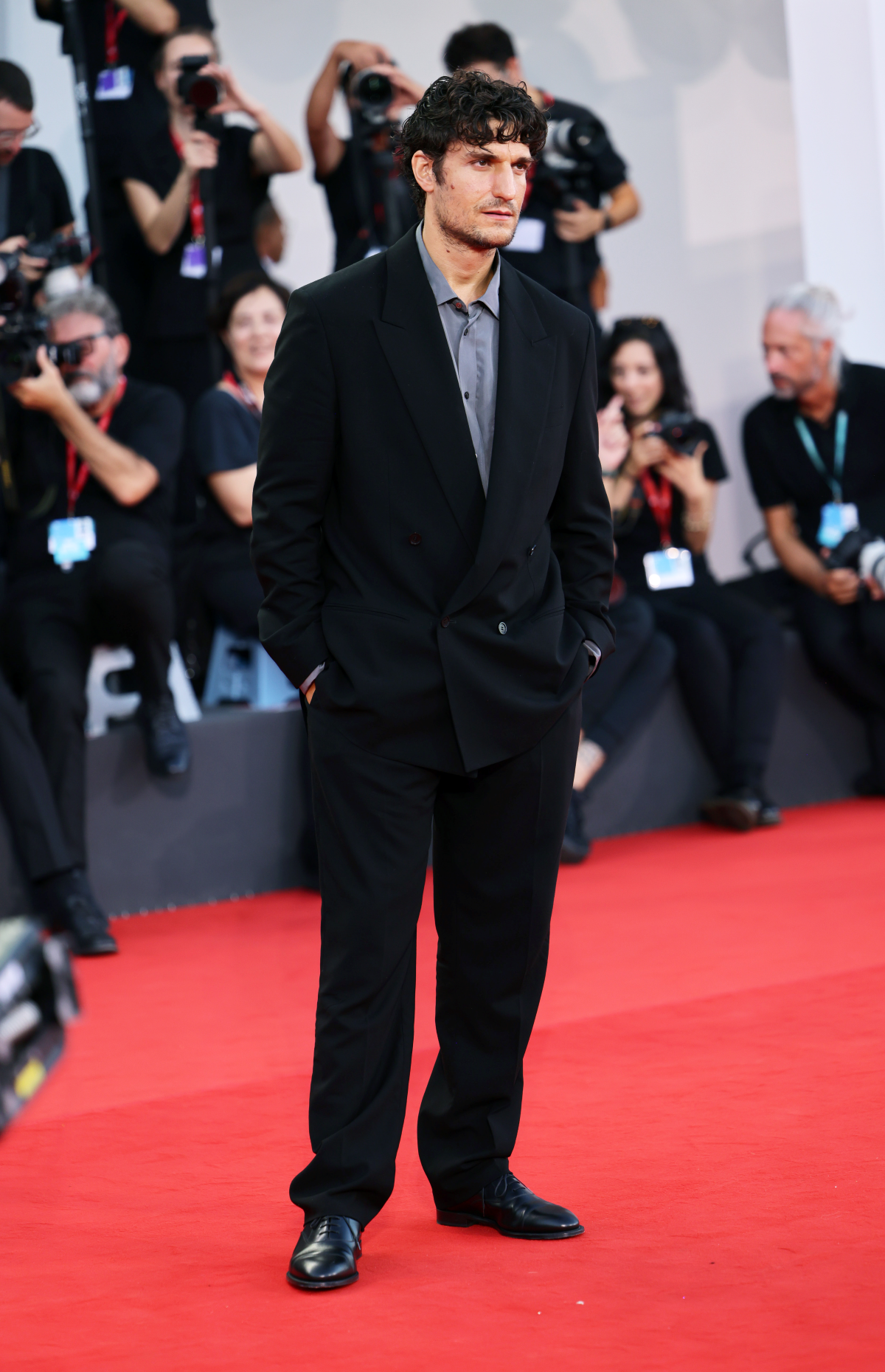 Louis Garrel posa en la alfombra roja del Festival de Venecia con un traje cruzado de lana azul marino, camisa de seda gris y zapatos Derby negros de Dior