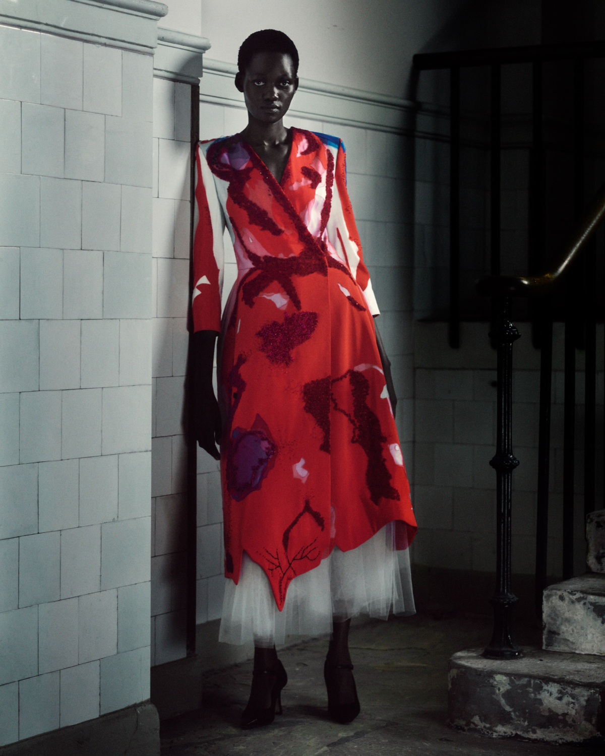 Modelo luce un vestido en tonos rojizos de Steve O Smith, de silueta fluida y con detalles ornamentales, durante la presentación de «Fever» en la Royal Academy of Arts