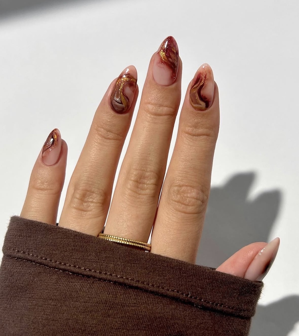 Manicura estilo pumpkin spice nails con purpurina. Imagen: @thenaillologist