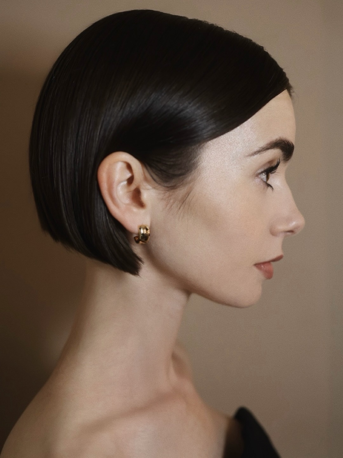 Lily Collins posa con un corte de pelo bob moreno, de líneas pulidas y acabado sofisticado, durante un evento promocional de «Emily en París»