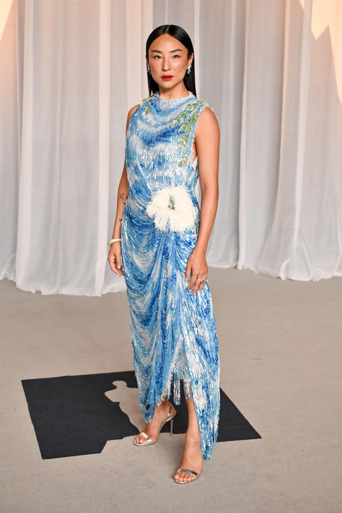 Greta Lee con vestido de alta costura de Dior en gasa de seda blanca, bordados de lentejuelas con motivos de paisajes celestes, flecos drapeados, gran flor de eucalipto en la cadera y bordes deshilachados en la Academy Museum Gala 2026
