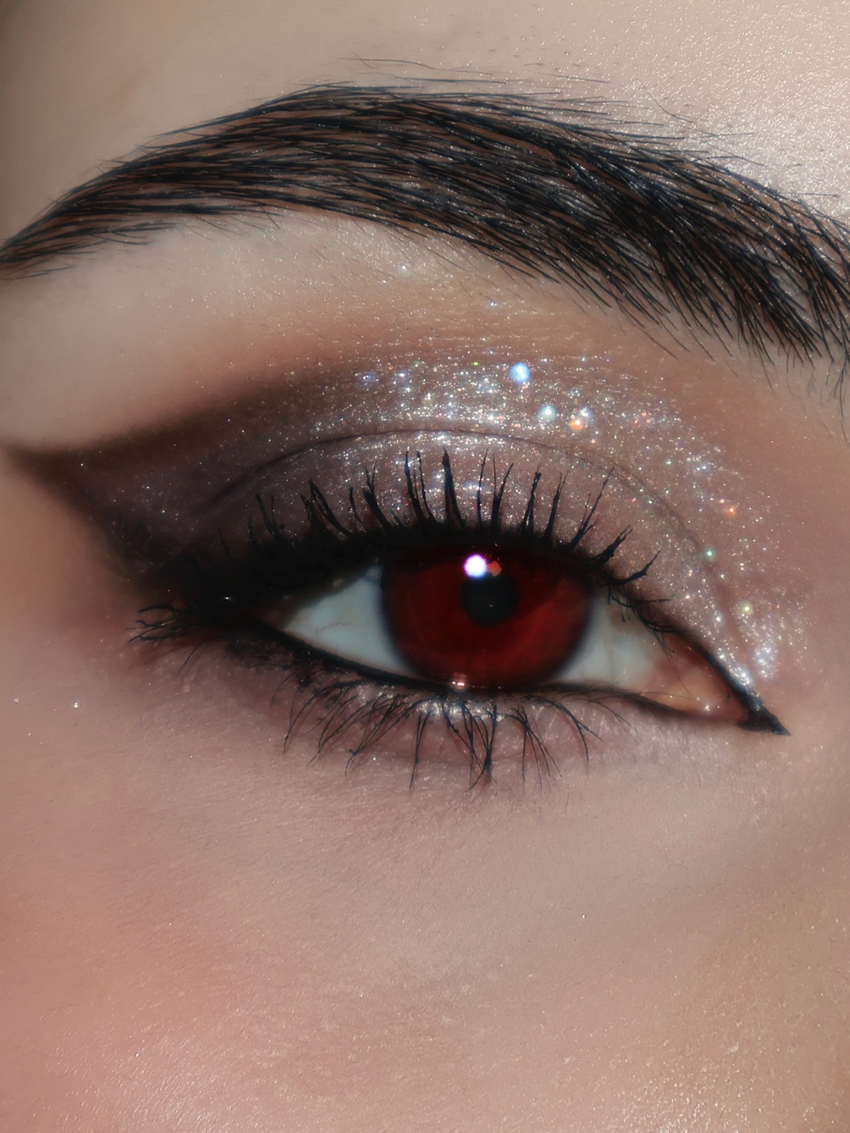 Maquillaje de Halloween inspirado en una vampiresa, con sombras de ojos en tonos oscuros, delineado negro marcado y pestañas voluminosas
