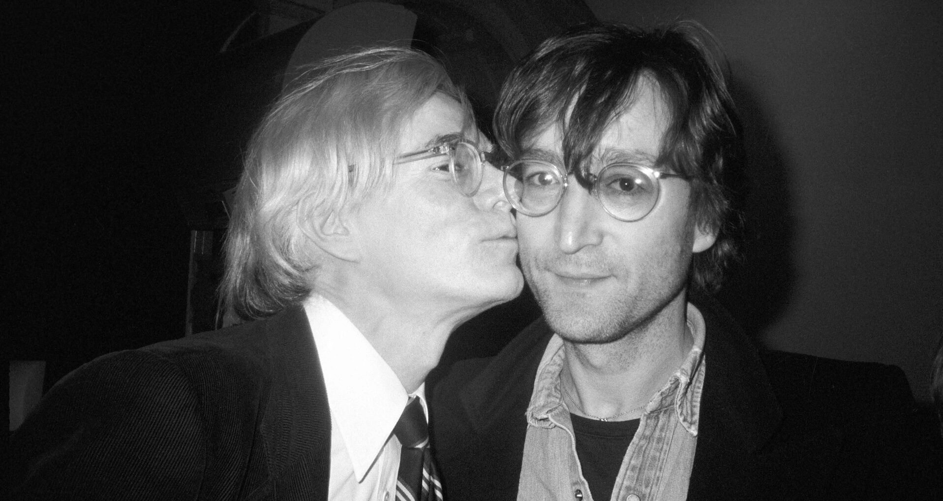 Andy Warhol dándole un beso en la mejilla al músico John Lennon