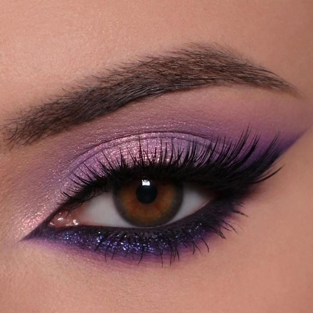 Maquillaje de ojos en tonos violetas, con sombras difuminadas que intensifican la mirada y crean un acabado dramático