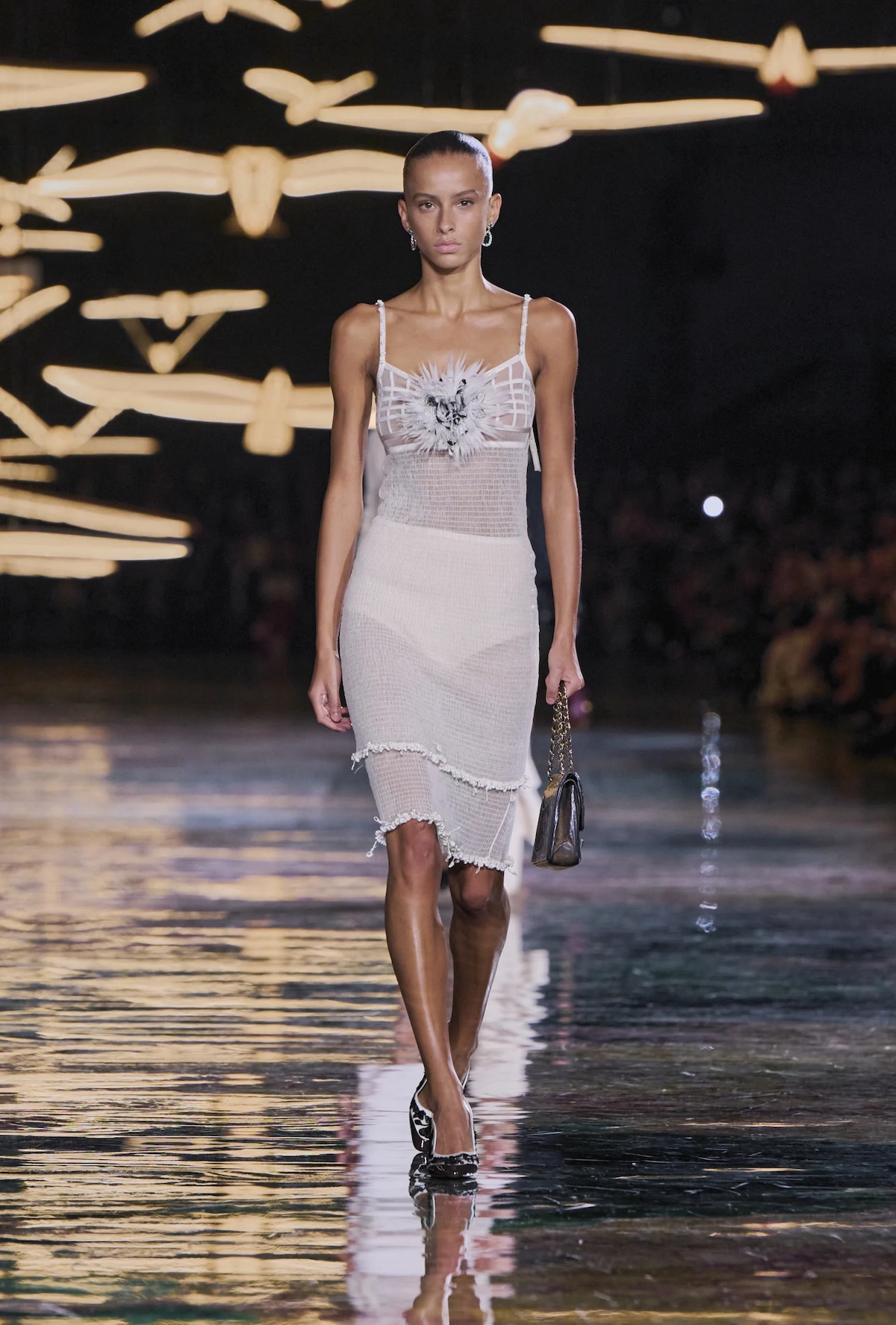 Look de Chanel SS27 con transparencias, falda de tweed blanco y bolso de cadena durante el desfile Primavera-Verano 2027