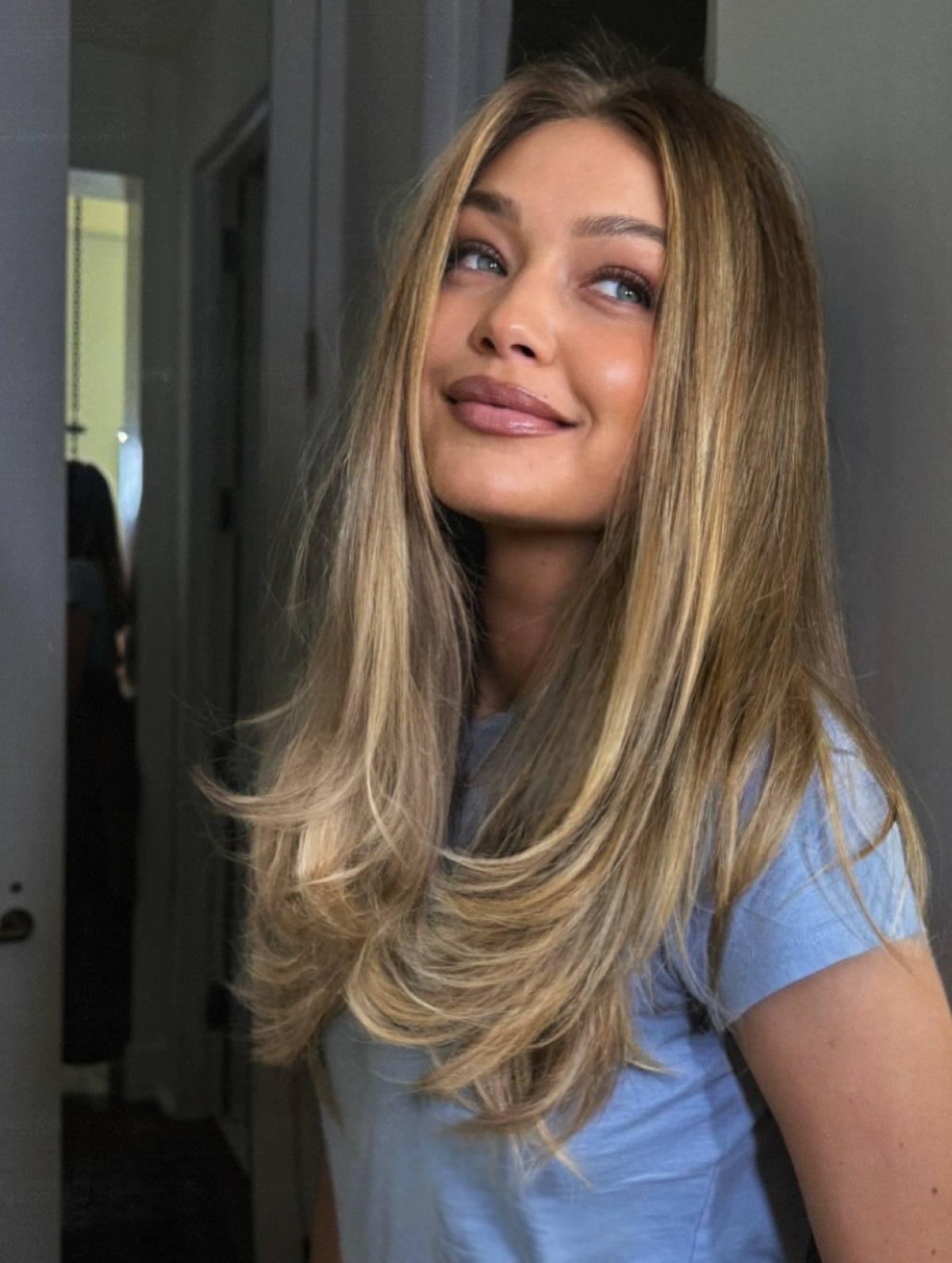 Gigi Hadid luce una melena rubia larga con «Love Layers», capas que comienzan por debajo de la barbilla y se alargan hacia las puntas, creando una silueta en forma de corazón, con volumen en la raíz y un acabado pulido